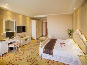 合肥市にあるGreentree Inn Anhui Hefei South High-speed Rail Station Fanhua Avenue Haiheng Express Hotelのベッドとデスクが備わる広い客室です。