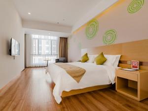 a hotel room with a large bed and a television at GreenTree Inn Taian High-speed Railway Station Lingshan Avenue Business Hotel in Tai'an