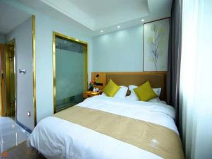 een slaapkamer met een groot wit bed met gele kussens bij GreenTree Inn Wuxi Jiangyin Changjing Town Selected Hotel in Wuxi