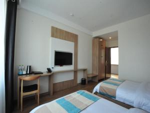 a hotel room with two beds and a desk with a television at VX Zibo Zhangdian District Jinjing Avenue Hotel in Zibo