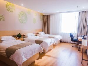 a hotel room with three beds and a table and chairs at GreenTree Inn Hengshui Olympic Sports Center South Ring Road Business Hotel in Hengshui