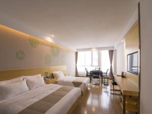 a hotel room with two beds and a table at GreenTree Inn Wuxi Rongchuang cultural Tourism City Nanquan Town Business Hotel in Wuxi