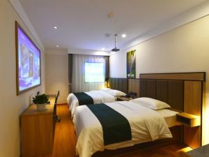 a hotel room with two beds and a television at GreenTree Inn Huludao Yuzhong County Central Road Smart Choice Hotel in Suizhong