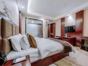 a bedroom with a large white bed and a television at GreenTree Eastern Kunming Baiyun Road Tongde Square Hotel in Kunming