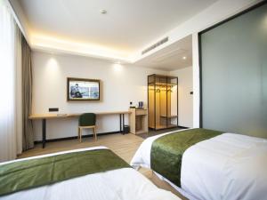 a hotel room with two beds and a desk at GreenTree Inn Ankang Bashan Middle Road in Ankang
