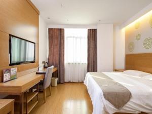 LuoxiにあるGreenTree Inn Changzhou Xixiasu Town Express Hotelのベッド、デスク、テレビが備わるホテルルームです。