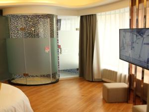 a bedroom with a shower and a tv in a room at Shell Shanghai Wanda Plaza Wujiaochang Metro Station Hotel in Shanghai