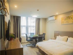 a hotel room with a bed and a table with chairs at Shell Wuhu City Jinghu District Rehabilitation Road Hotel in Wuhu