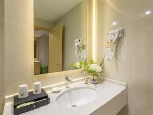 a bathroom with a sink and a mirror at GreenTree Inn Xuzhou Ou Shasha Building Materials City Express Hotel in Xuzhou