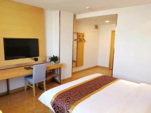 a hotel room with a bed and a desk with a television at GreenTree Xining Chengzhong Area Dongguan Street Street Hotel in Xining