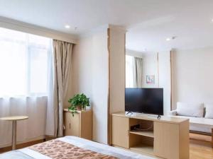 a bedroom with a bed and a flat screen tv at GreenTree Inn Gannan Hezuo Pedestrian Street Express Hotel in Hezuo +37 photos
