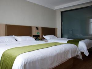 two beds in a hotel room with a large window at GreenTree Inn Heze Cao County Railway Station Business Hotel in Cao