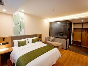 a bedroom with a large bed and a living room at GreenTree Inn Fuyang City Yingzhou District Kuixing Road Business Hotel in Fuyang
