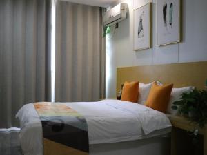 una camera da letto con un letto con cuscini arancioni e una finestra di Shell Suzhou Chinese Medicine Hospital Hotel a Suzhou