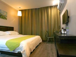 1 dormitorio con 1 cama y escritorio con TV en GreenTree Wulumuqi Airport Hotel, en Ürümqi