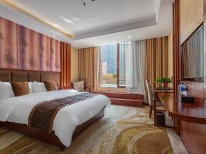 a bedroom with a bed and a desk and a window at GreenTree Eastern Kunming Baiyun Road Tongde Square Hotel in Kunming