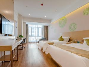 a hotel room with two beds and a desk at GreenTree Inn Taian High-speed Railway Station Lingshan Avenue Business Hotel in Tai'an