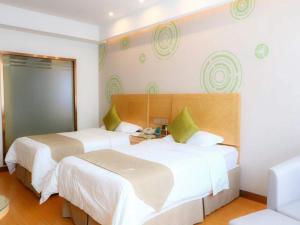 a hotel room with two beds with green pillows at GreenTree Inn Anhui Fuyang Yingshang Yingyang Road Suzhou Manor Business Hotel in Jingzhuang
