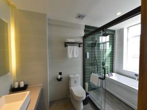 a bathroom with a toilet and a sink and a tub at GreenTree Inn Huludao Yuzhong County Central Road Smart Choice Hotel in Suizhong
