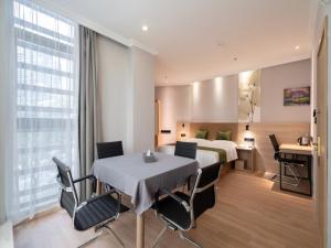 ein Hotelzimmer mit einem Bett und einem Tisch und Stühlen in der Unterkunft GreenTree Inn Jiangsu Wuxi Taihu Avenue Tongyang Road Express Hotel in Wuxi