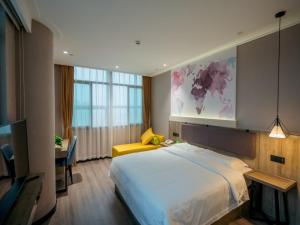 a bedroom with a large bed and a desk at Vatica Wuxi Yixing City Renmin Road Hotel in Yixing