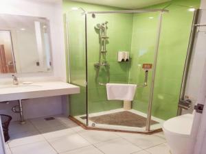 a green bathroom with a shower and a sink at GreenTree Inn Liaocheng Economic Development Zone Huitong Logistics Park Express Hotel in Liaocheng