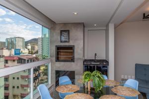 balcón con mesas y sillas y vistas a la ciudad en Nilmare Apartamentos e Suites para suas Férias, en Itapema