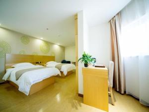 a hotel room with two beds and a desk with a plant at GreenTree Inn Liaocheng Economic Development Zone Huitong Logistics Park Express Hotel in Liaocheng