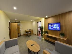 sala de estar con sofá y TV en la pared en GreenTree Inn Huludao Yuzhong County Central Road Smart Choice Hotel en Suizhong