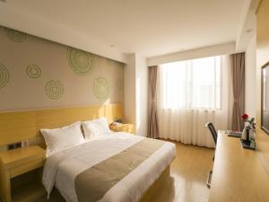 a bedroom with a bed and a desk and a window at GreenTree Inn Wuxi Rongchuang cultural Tourism City Nanquan Town Business Hotel in Wuxi