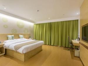 徐州的住宿－格林豪泰徐州高铁站东广场智选酒店，一间卧室配有一张床、一张书桌和绿色窗帘