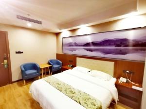 a hotel room with a bed and two blue chairs at GreenTree Alliance Changzhou Jintan District Dongmen Street Hotel Hotel in Changzhou