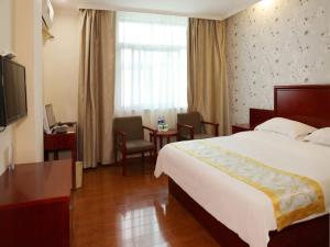 ein Hotelzimmer mit einem Bett, einem Schreibtisch und einem TV in der Unterkunft GreenTree Inn Anhui Fuyang Taihe South Xiyang Road Business Hotel in Balipu