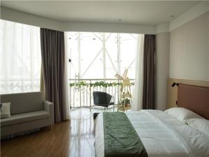 een slaapkamer met een bed en een stoel en een groot raam bij GreenTree Inn Lu'an Kaihong Plaza Express Hotel in Lu'an