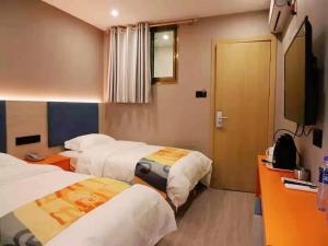 a hotel room with three beds and a flat screen tv at Shell Lanzhou Qilihe District Lanzhou High Speed Railway Station Hotel in Lanzhou