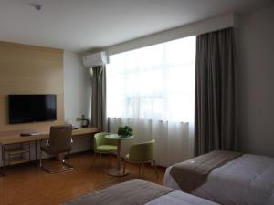 a hotel room with a bed and a desk and a television at GreenTree Inn Zaozhuang High Speed Rail Station Express Hotel in Taozhuang