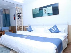 a bedroom with a large bed with blue and white sheets at Shell Chengde Longhua County Xingzhou Road Hotel in Chengde