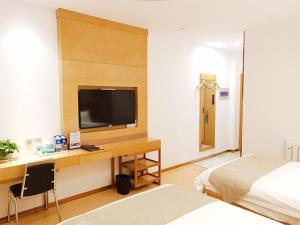 a bedroom with a desk with a tv and a bed at GreenTree Inn Tangshan Qianxi Bus Terminal Express Hotel in Qian'an