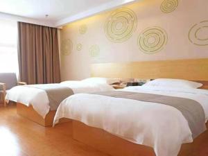 two beds in a hotel room with white sheets at GreenTree Inn Jiangxi Yingtan Xinjiang Area Government No. 1 Middle Business Hotel in Yingtan