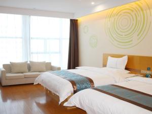 a hotel room with two beds and a couch at GreenTree Inn Yulin South Changcheng Road Business Hotel in Yulin