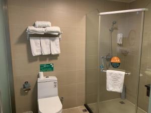 a bathroom with a shower and a toilet and towels at GreenTree Inn Jiangsu Nanjing Jiangning Southeast University Express Hotel in Jiangning