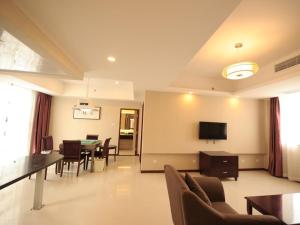 GreenTree Inn JiangSu SuZhou Science and Technology City Business Hotel في سوتشو: غرفة معيشة مع طاولة وكراسي وتلفزيون +43 صورة