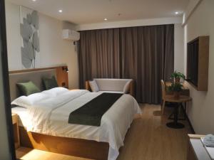 una habitación de hotel con una cama grande y una silla en GreenTree Inn Shangqiu Zhecheng Shanghai Road, en Shangqiu