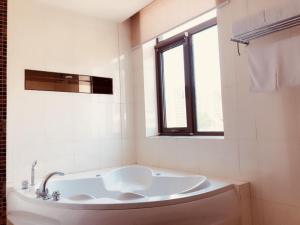 Una bañera blanca en un baño con ventana. en GreenTree Inn Beijing Haidian District Xueqing Road Business Hotel, en Beijing