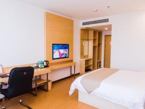 a bedroom with a bed and a desk with a computer at GreenTree Inn Hengshui Olympic Sports Center South Ring Road Business Hotel in Hengshui