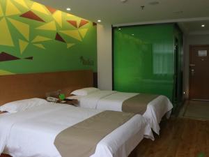 twee bedden in een kamer met een groene muur bij Vatica Hefei West Anqing Nongda East Gate Hotel in Hefei