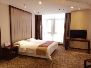 a hotel room with a bed and a flat screen tv at GreenTree Alliance Xuzhou Gulou District Sanhuan North Road, Jinju Wuliuwan Hotel in Xuzhou