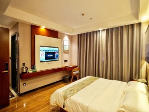 ein Hotelzimmer mit einem Bett und einem Flachbild-TV in der Unterkunft GreenTree Alliance Changzhou Jintan District Dongmen Street Hotel Hotel in Changzhou