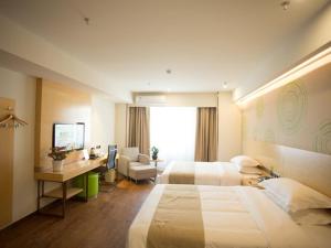 una camera d'albergo con 2 letti e una scrivania di GreenTree Inn Jinan Tangye Express Hotel a Jinan