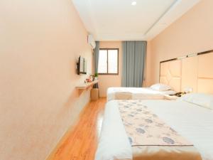 a hotel room with two beds and a window at Shell Jiaxing Jiashan Shenyou Road Hotel in Jiaxing